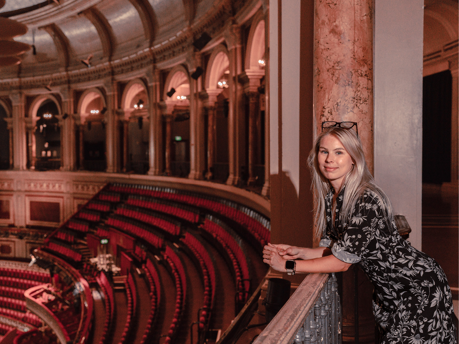 Woman leans on bannister overlooking theatre seats