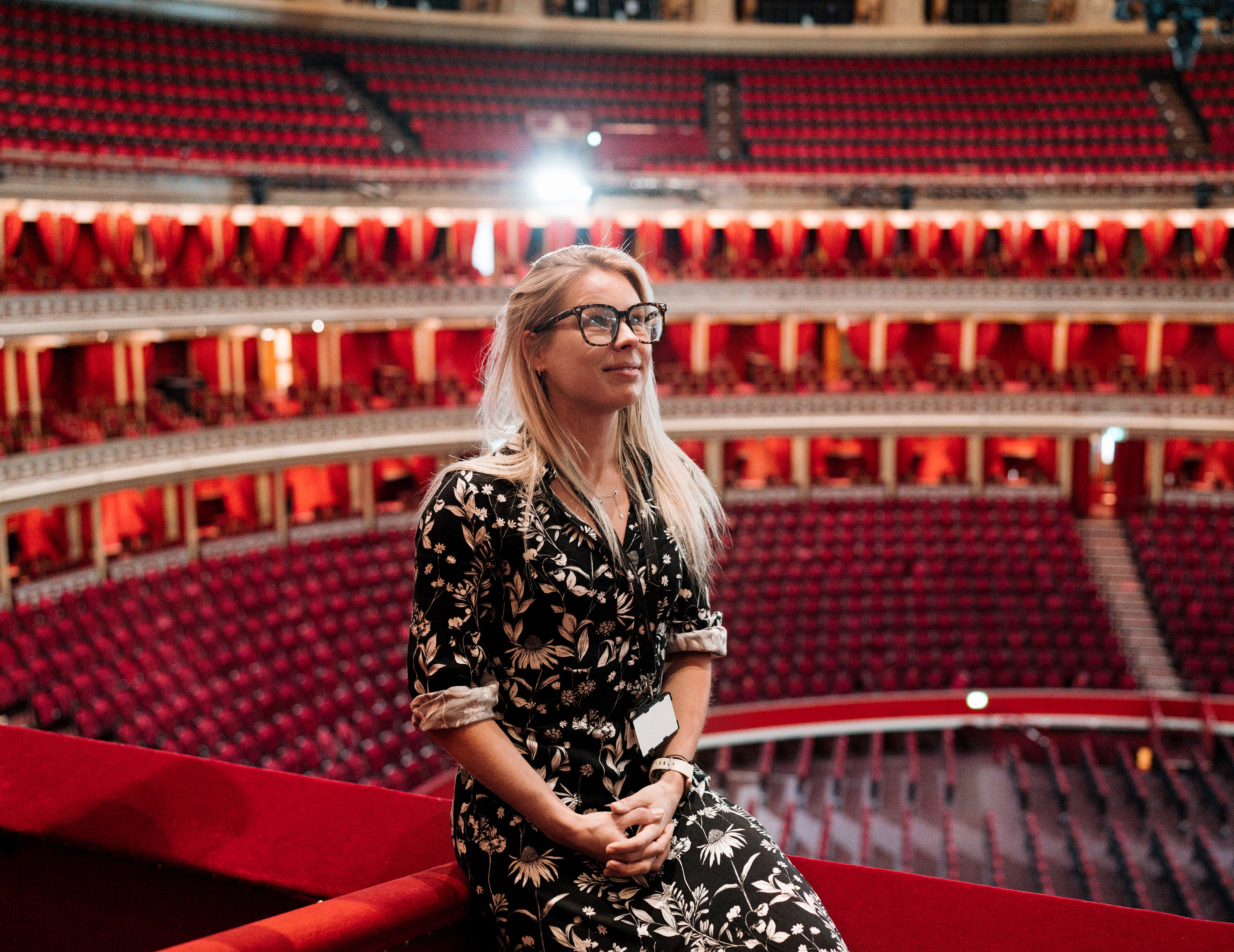 Woman sat on red ledge with backdrop of theatre seats 
