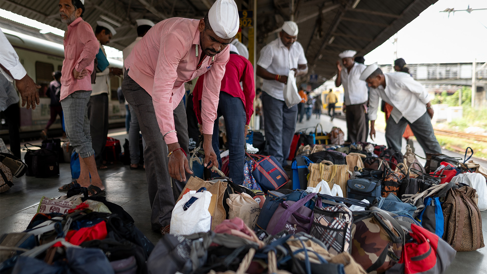 Photo of Dabbawalas sorting lunch bags on station platform
