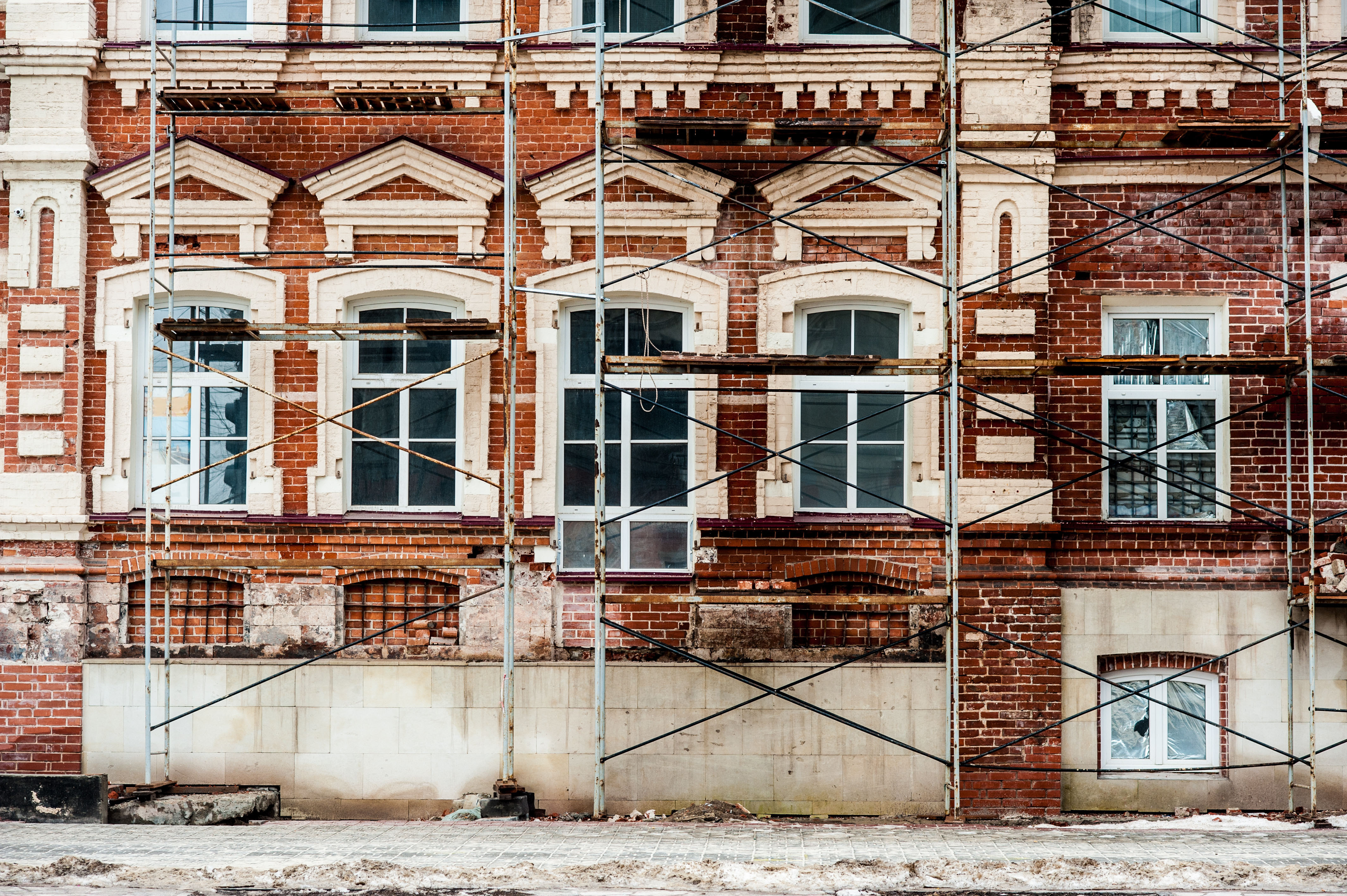 Restoration of old building  with white windows and red blocks and scaffolding