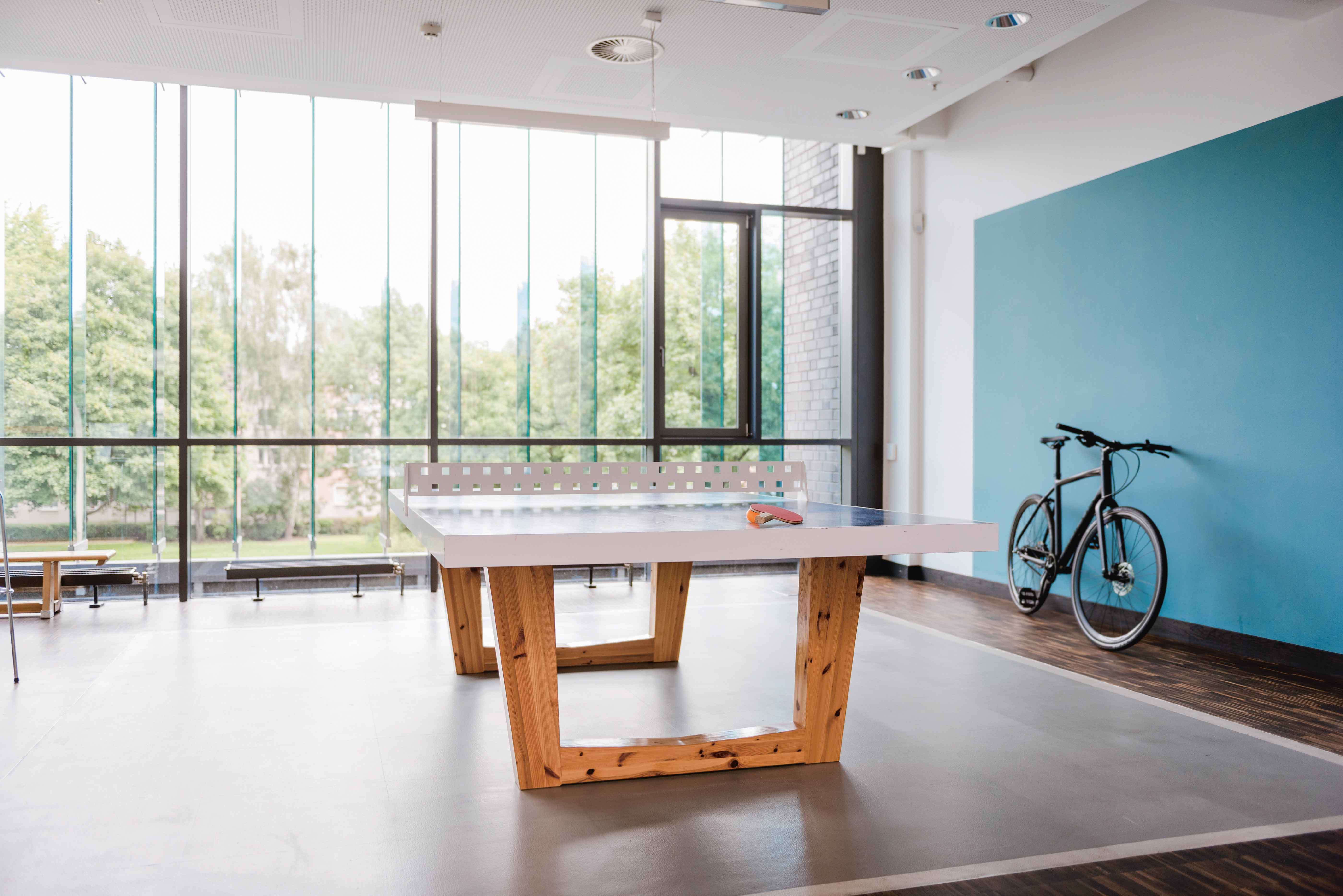 Table tennis ping pong table and bicycle in front of picture window in office recreation space