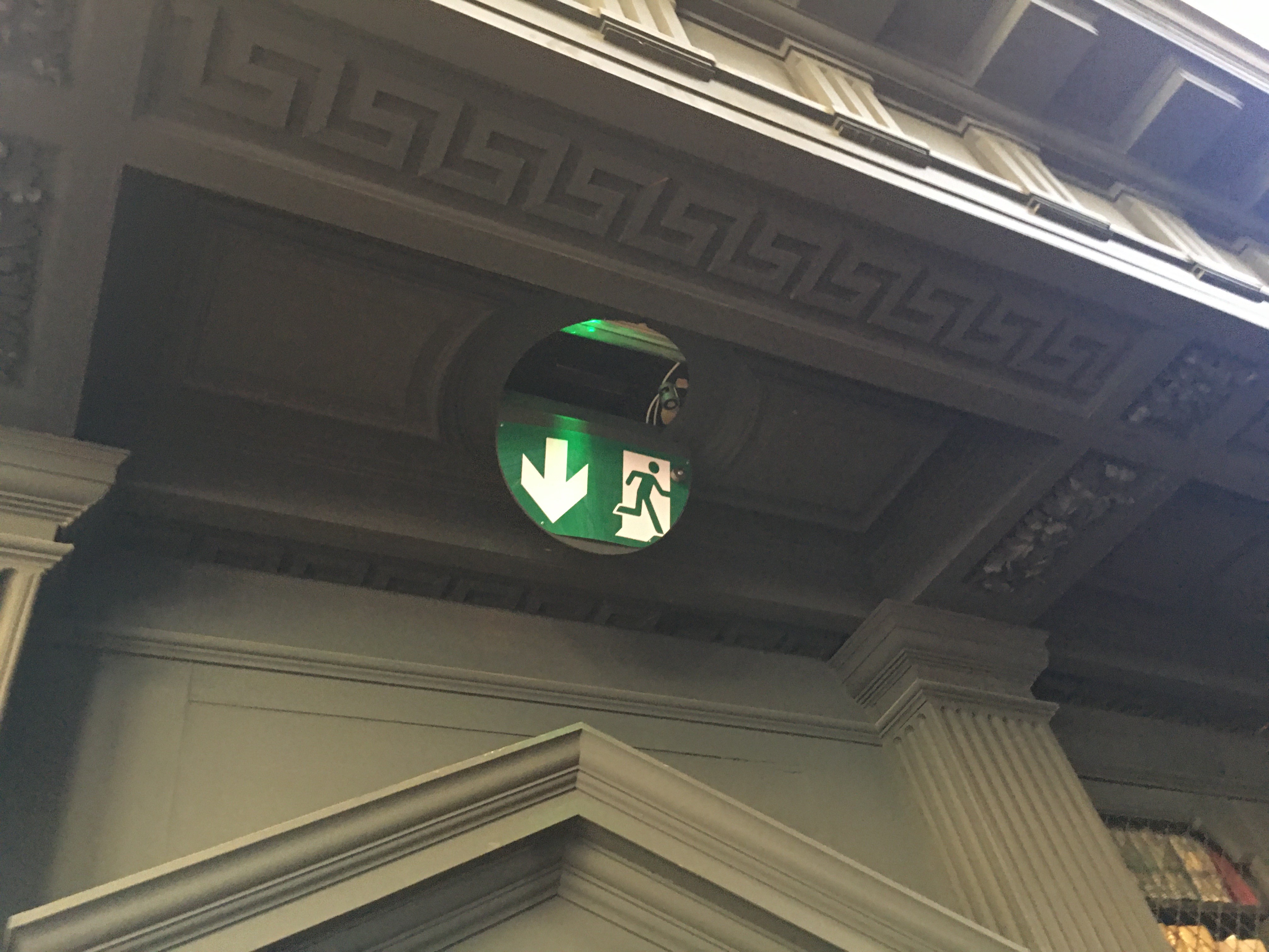 An unsuitable exit sign, sitting above the ceiling on the top side of a fibrous plaster roundel