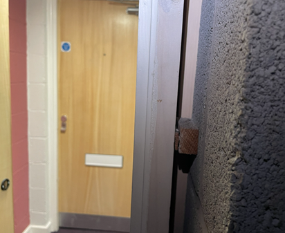 No firestopping between fire door frame and structural opening (visible within an electrical riser cupboard)