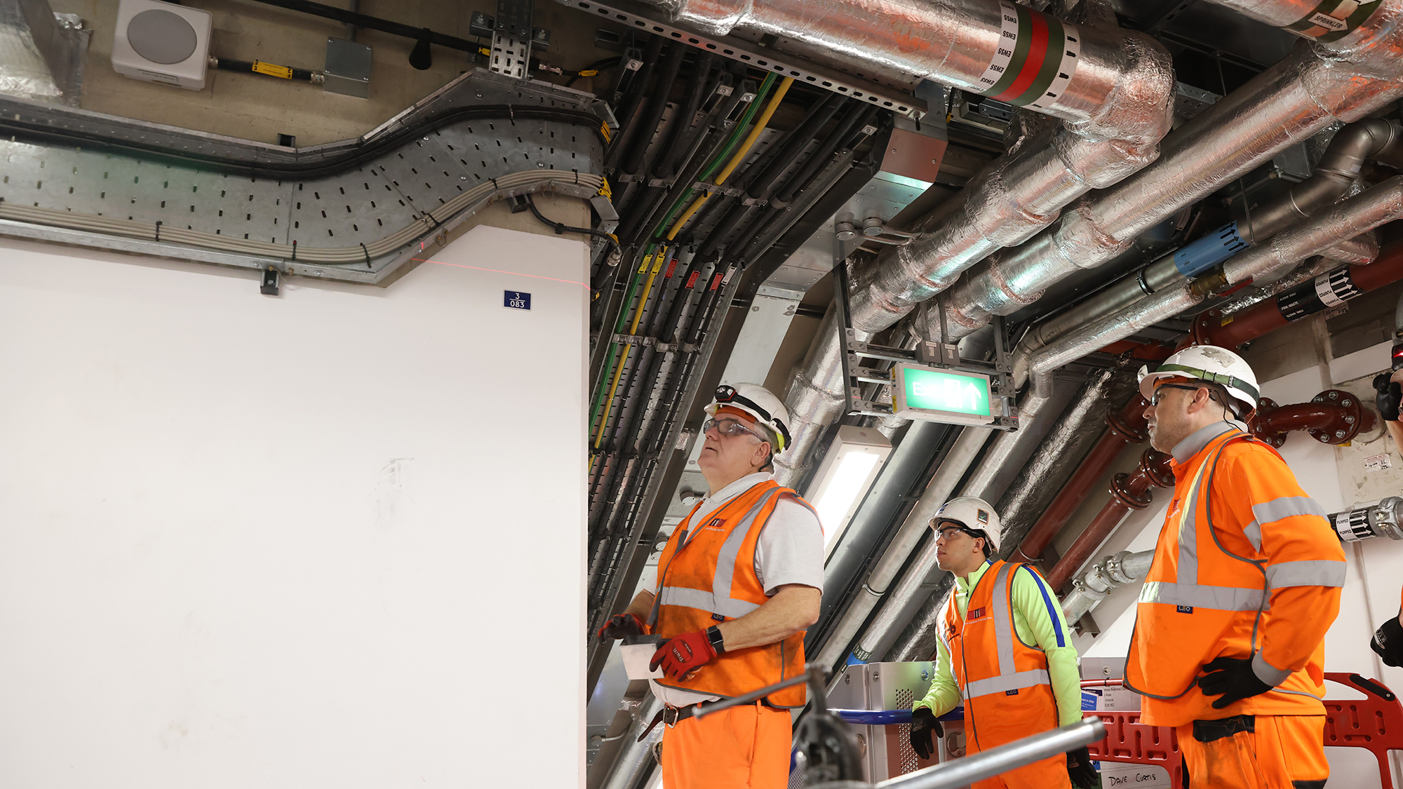 Three workmen in high vis gear installing cable networks in London Underground