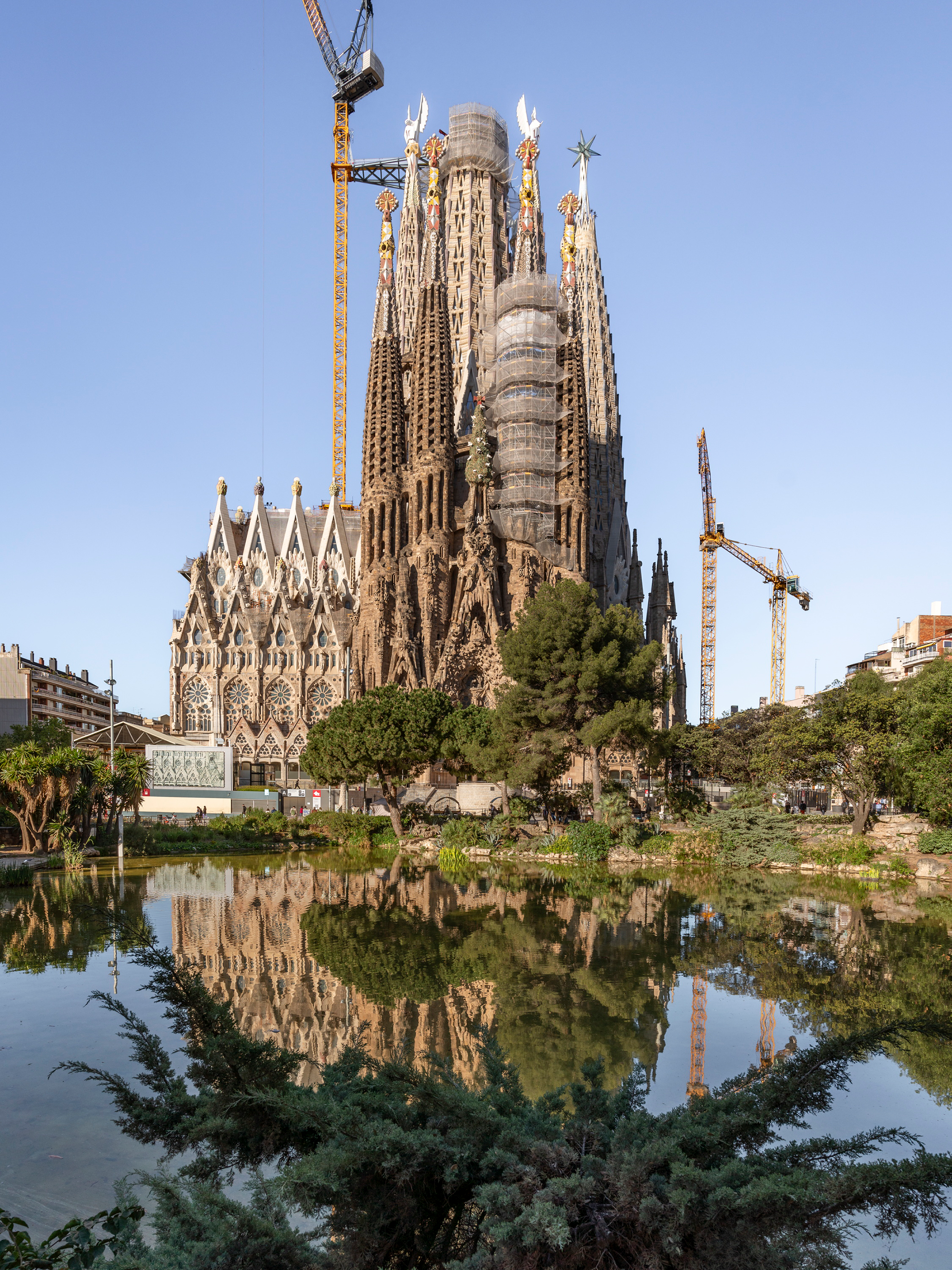 Exterior of Sagrada Família with spire-like towers overlooking the pond