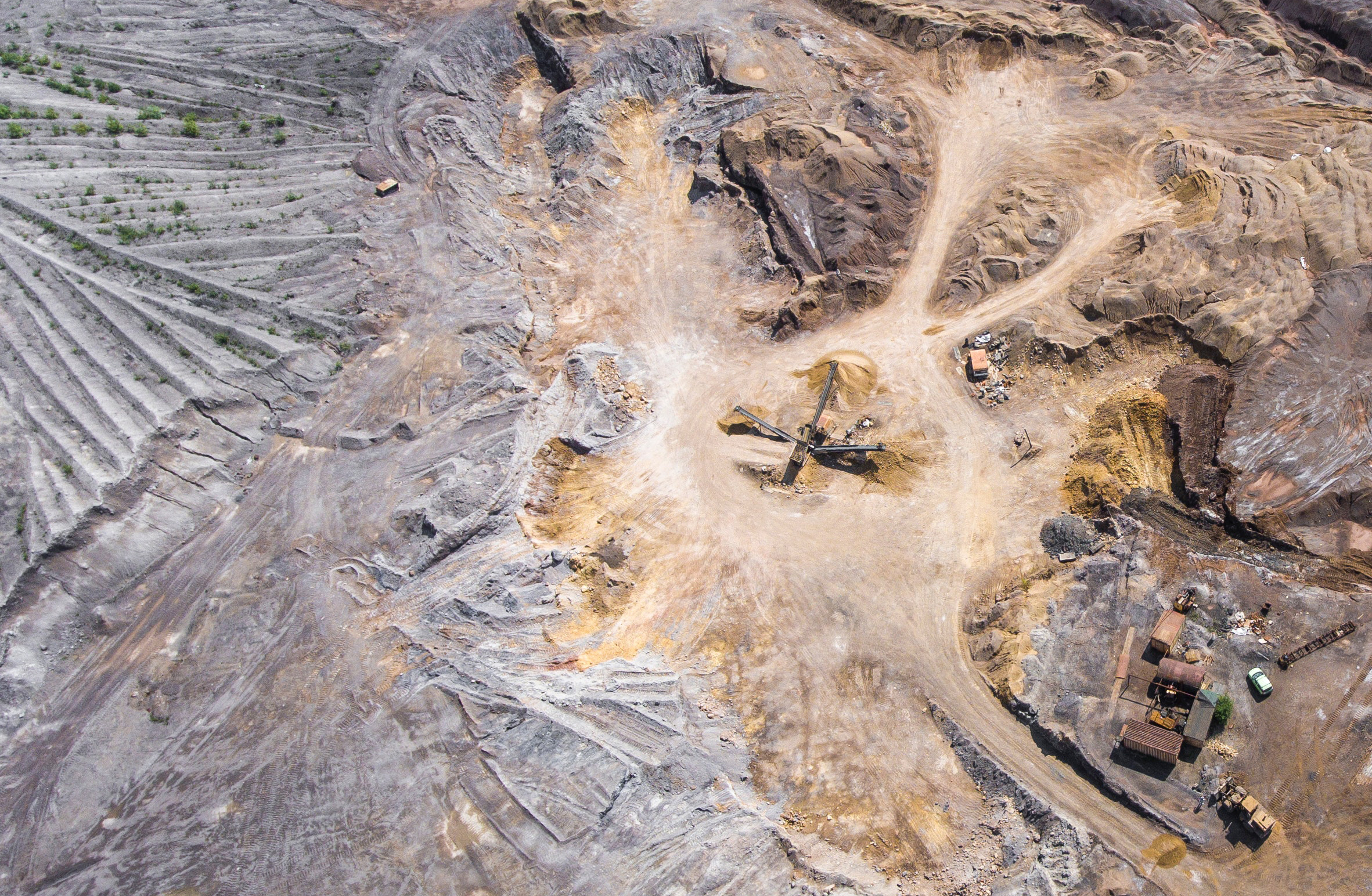 wide aerial shot of a quarry/mine with open fields next to it