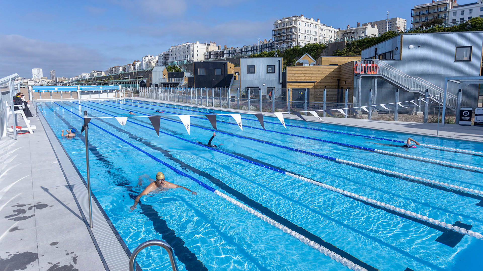 Person swimming in outdoor pool with Brighton skyline in background