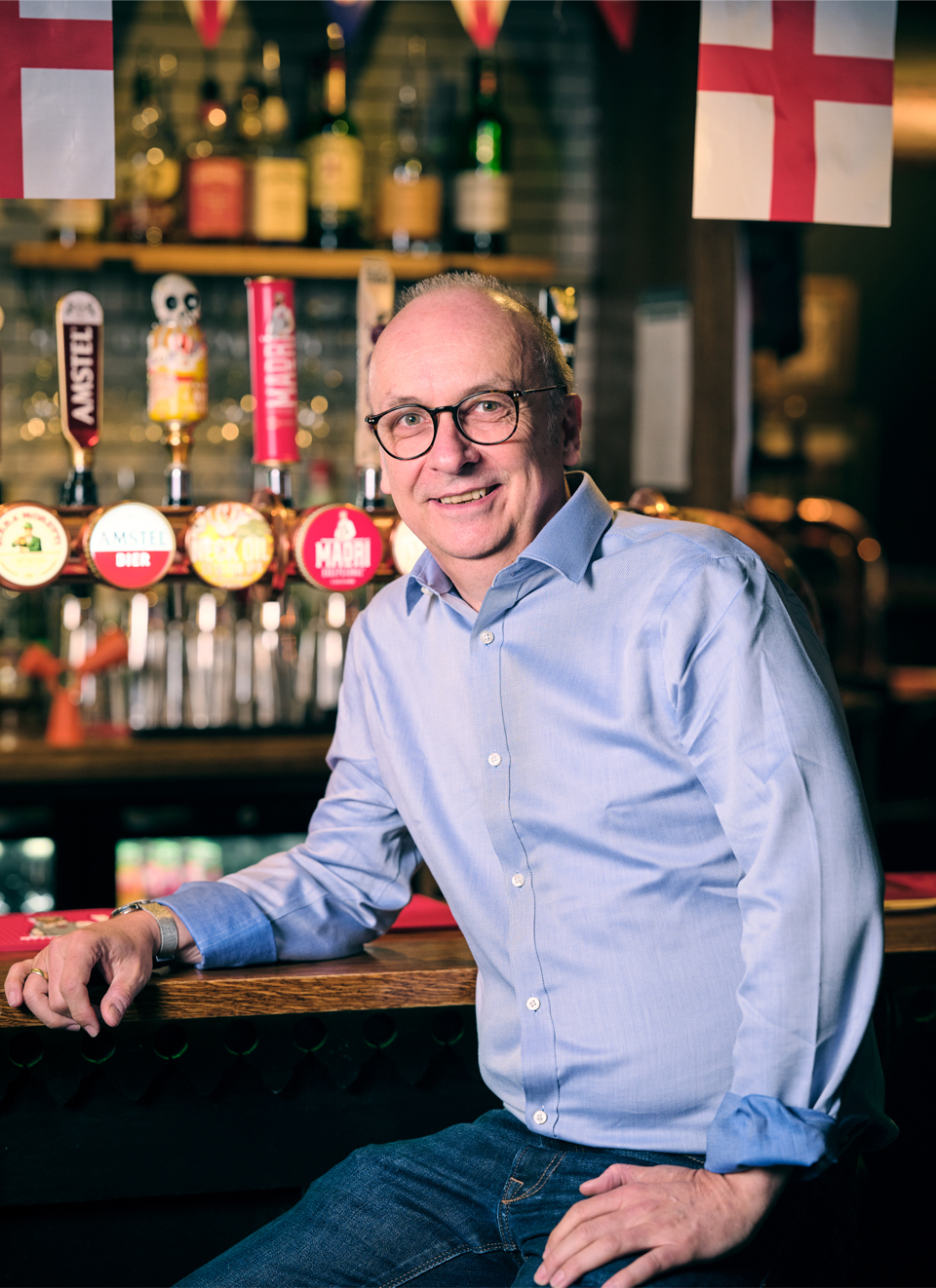 Stephen propped up on the bar with a pint of beer next to him and beer pumps in the background