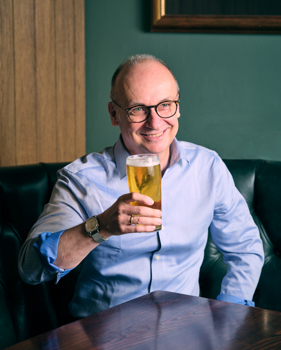 Stephen looks off camera holding a pint of beer in his hand