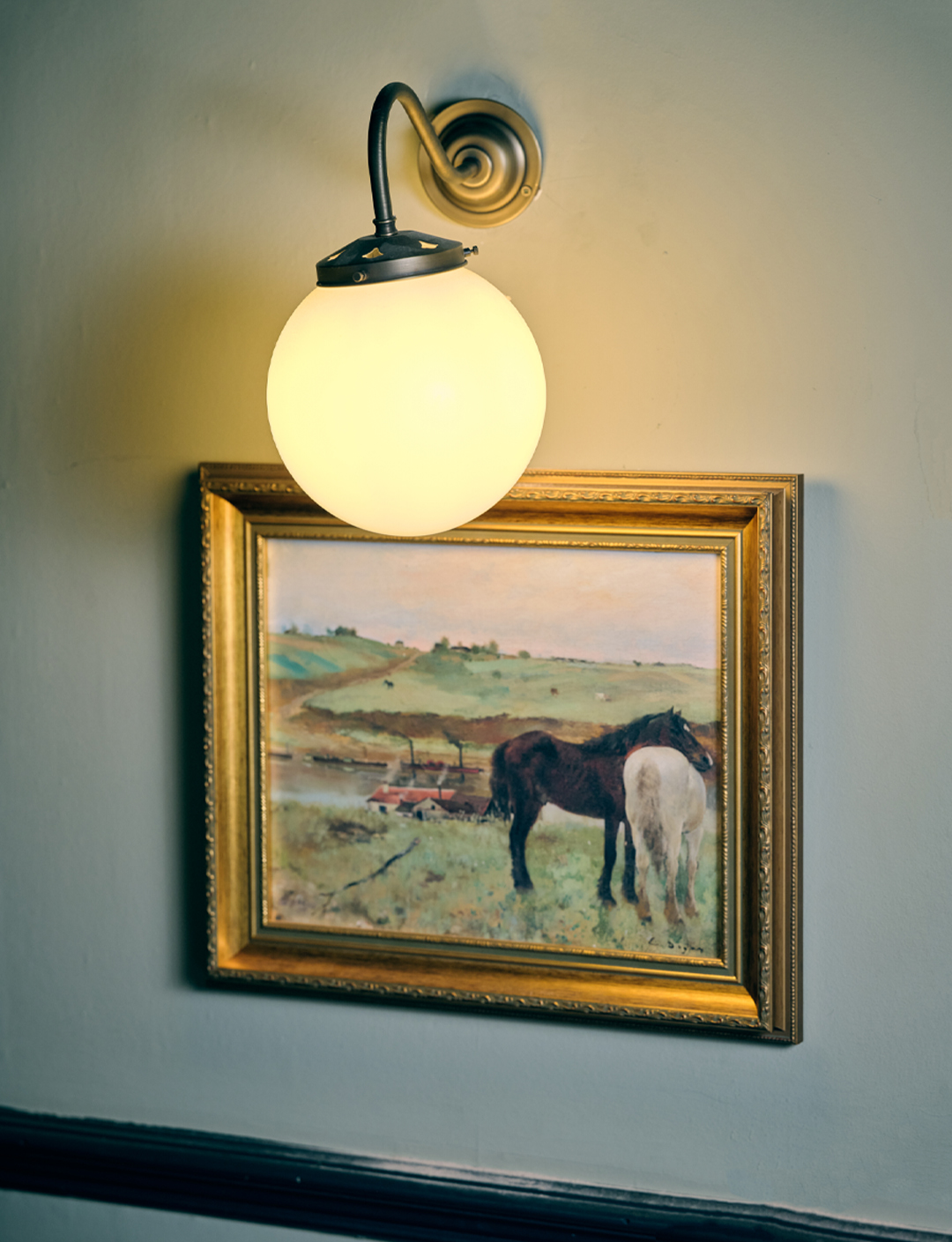 Painting of a horse inside an art frame with an overhanging light