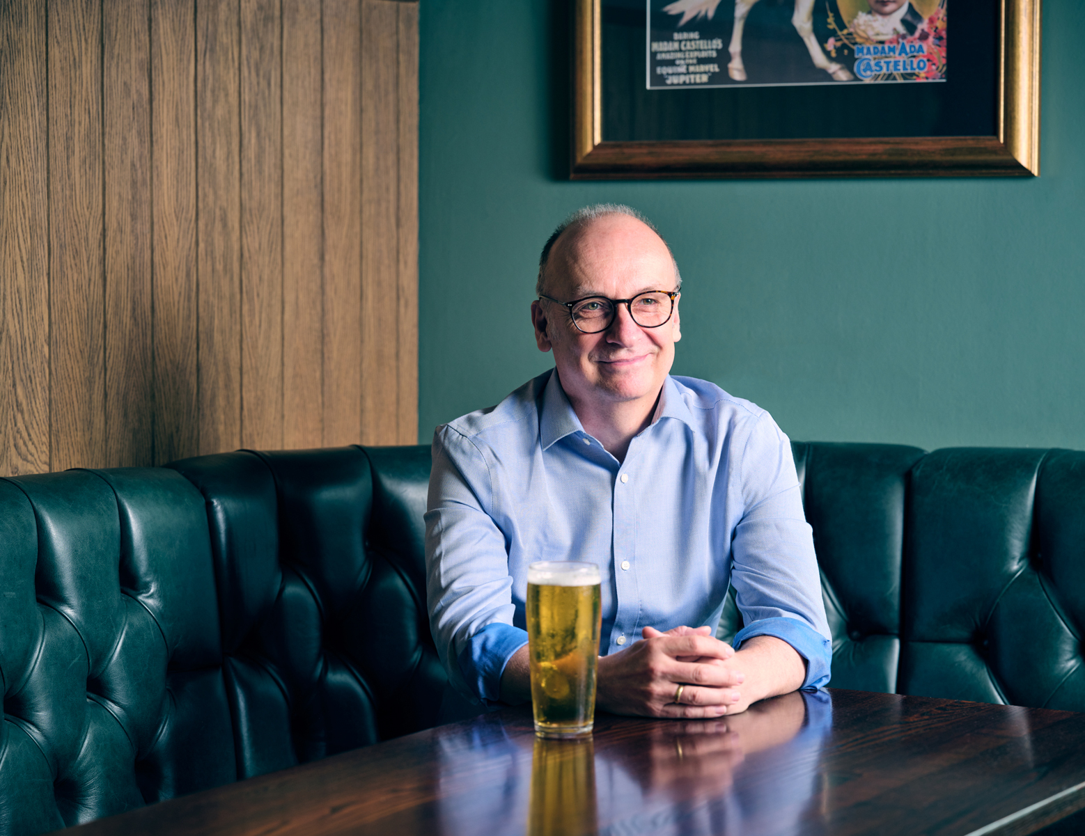 Stephen sat at a table in a leather booth with a pint of beer next to him