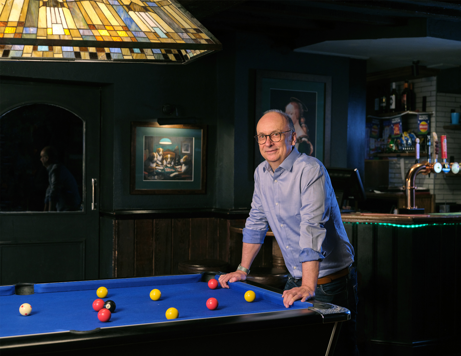 Stephen leaning on pool table with pub bar in background