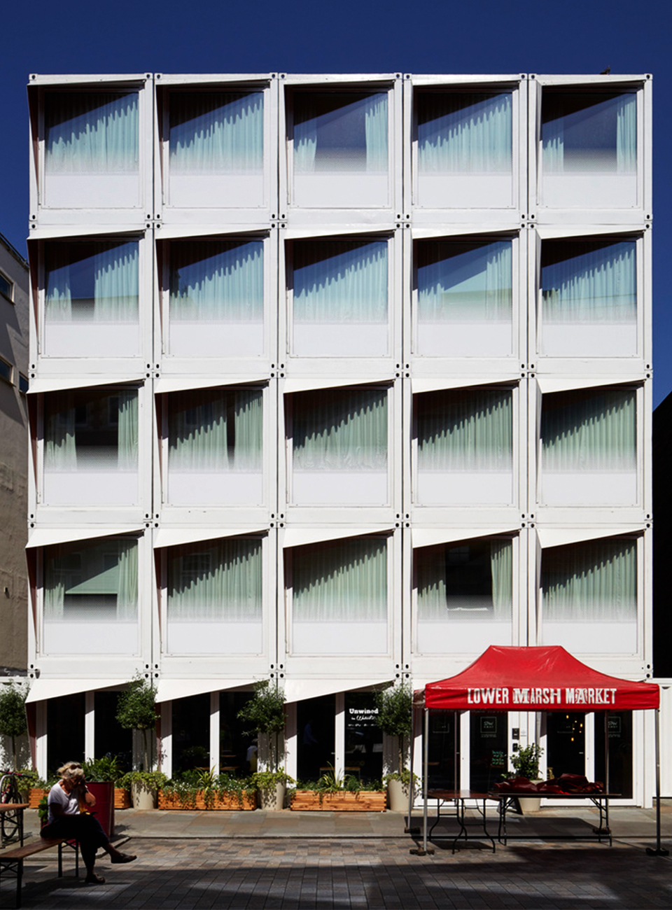 Rows of white shipping containers stacked on top of each other converted into hotel rooms