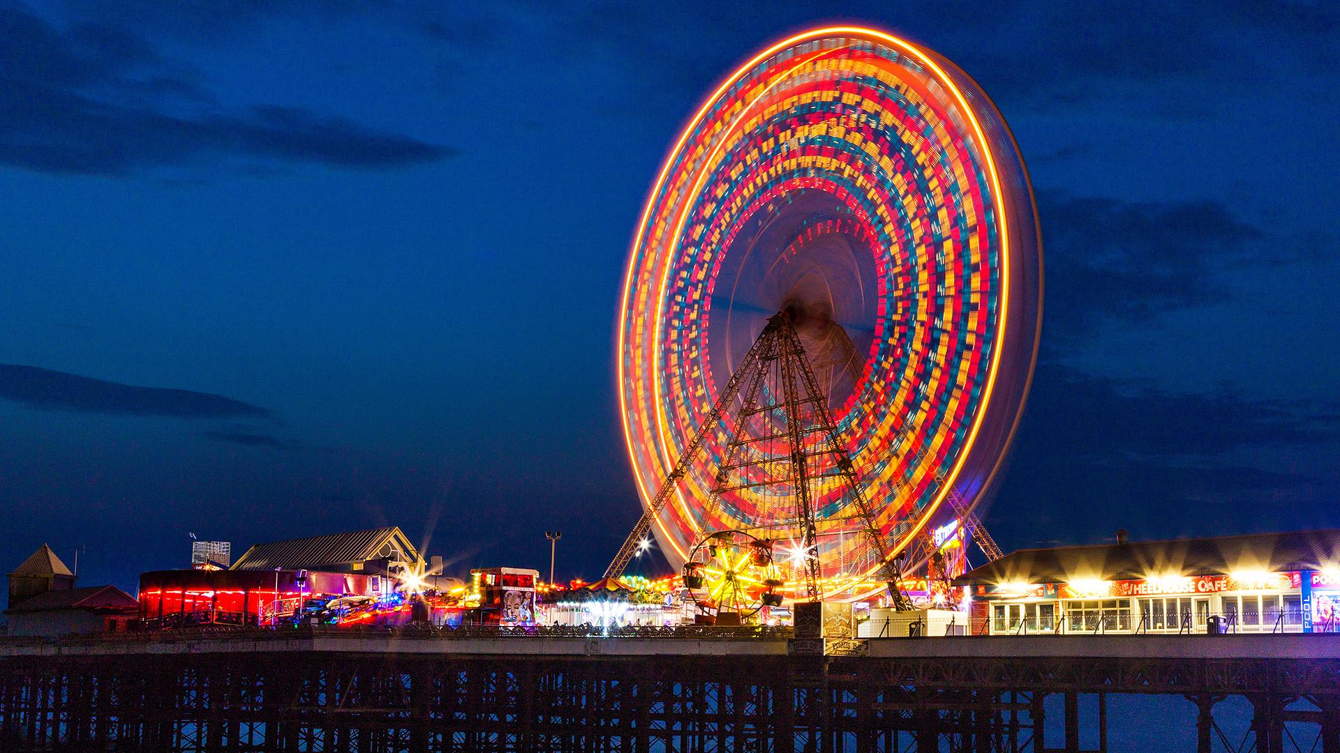 Time lapse of ferris wheel lit up at night on pier