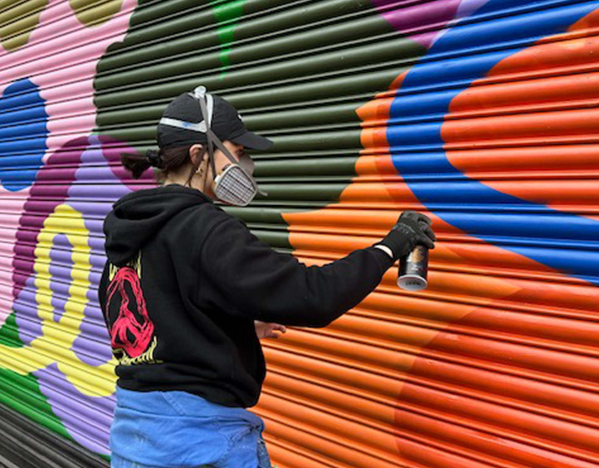 Woman spray paints onto shop shutter