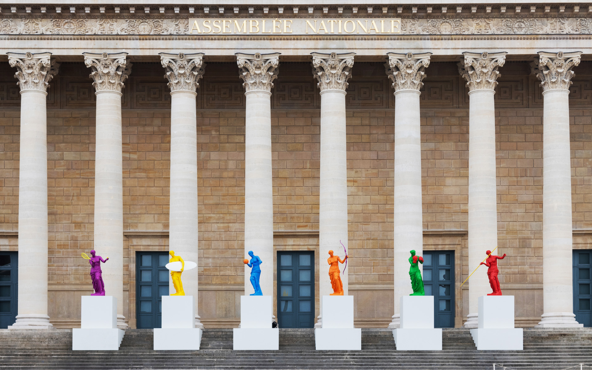 French parliament building or Assemblée Nationale with various colored Venus de Milo statues playing at different sports to celebrate the 2024 Olympic Games