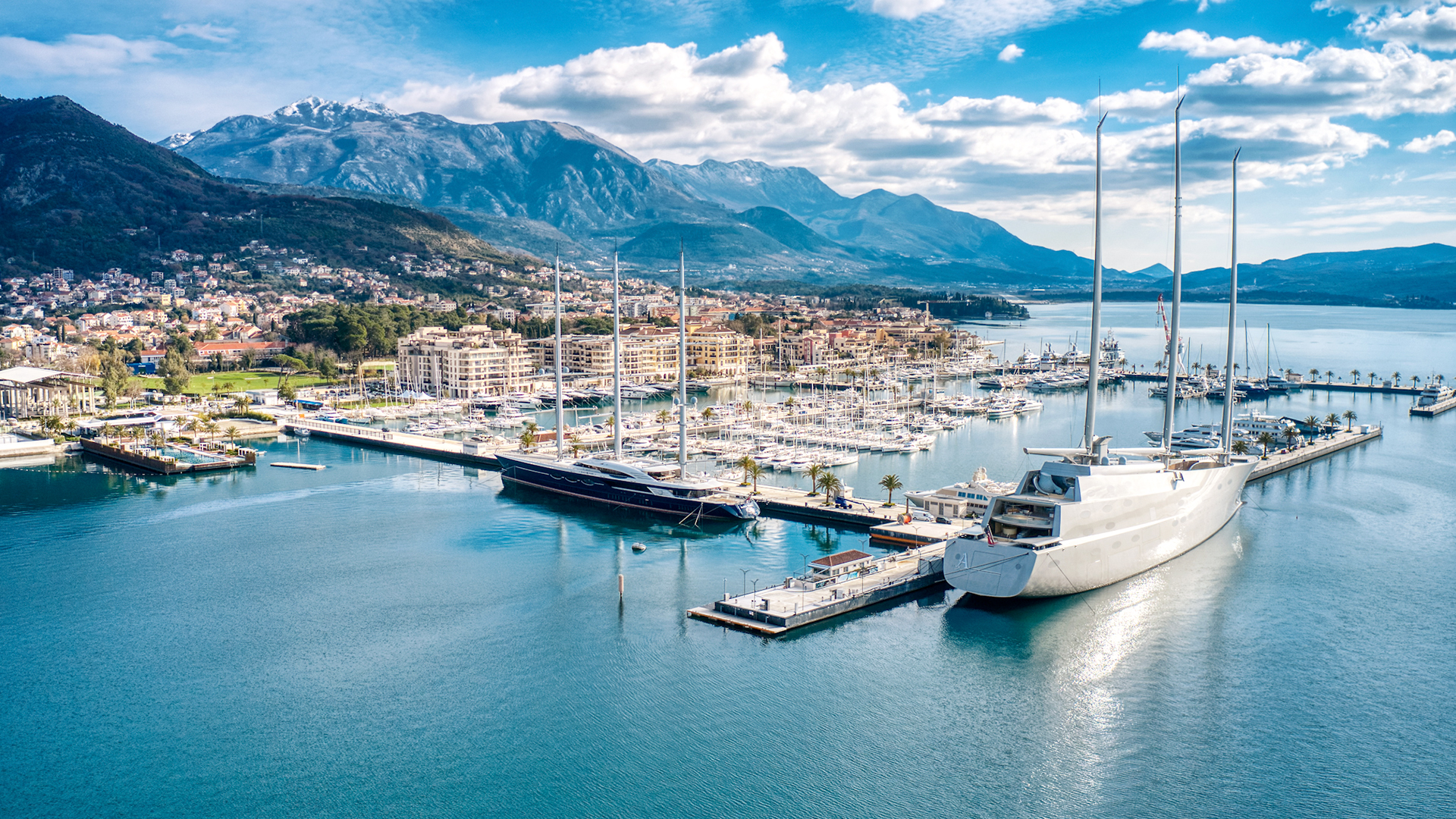 Super yachts docked in the marina with a mountain backdrop