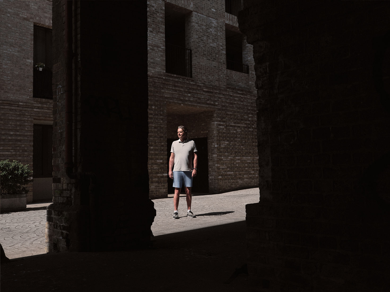 Ed standing outside housing estate framed by dark shadows