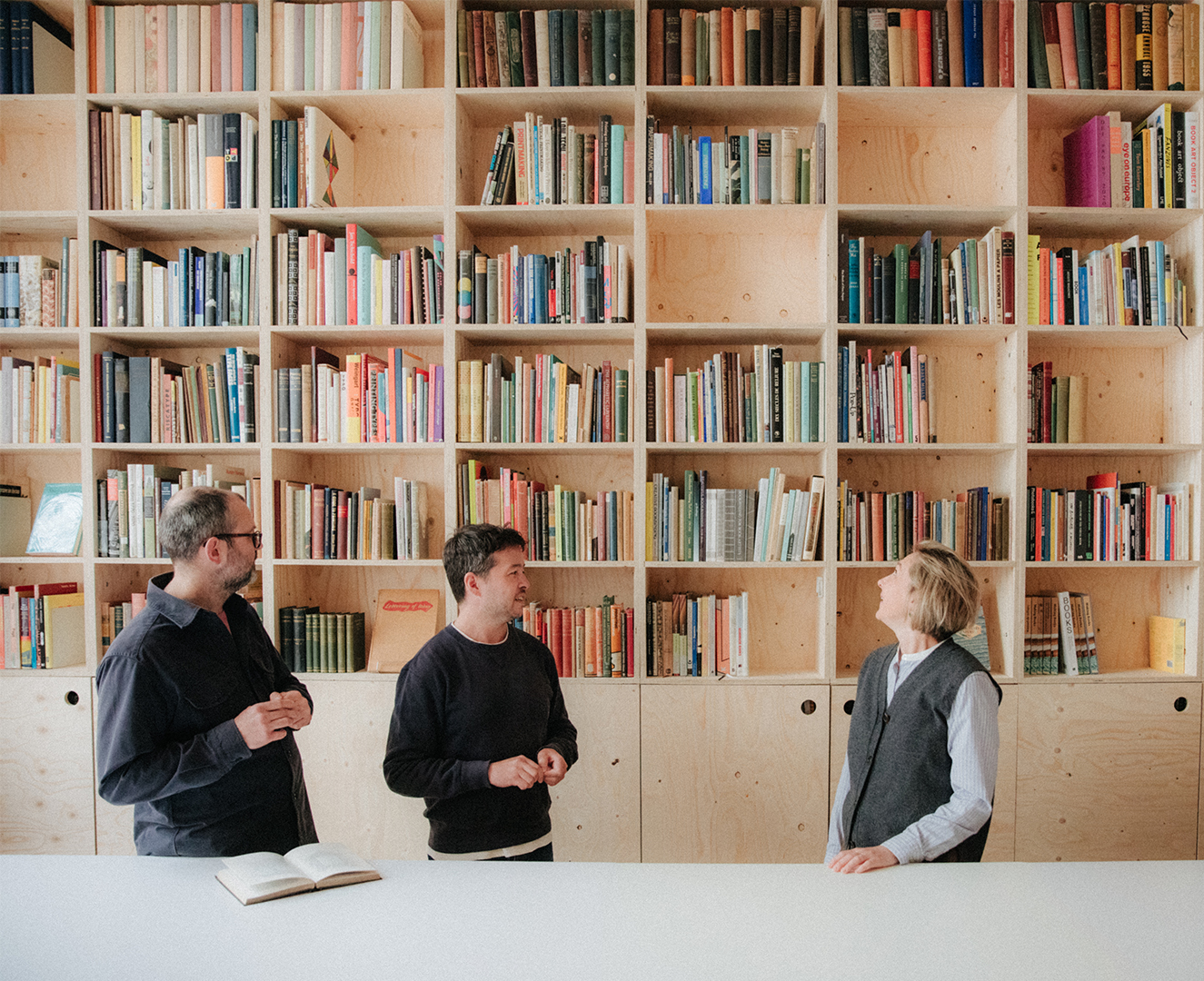 Yulia Pak MRICS London Centre for Book Arts Yulia speaks with owners Simon and Ira in front of book shelves
