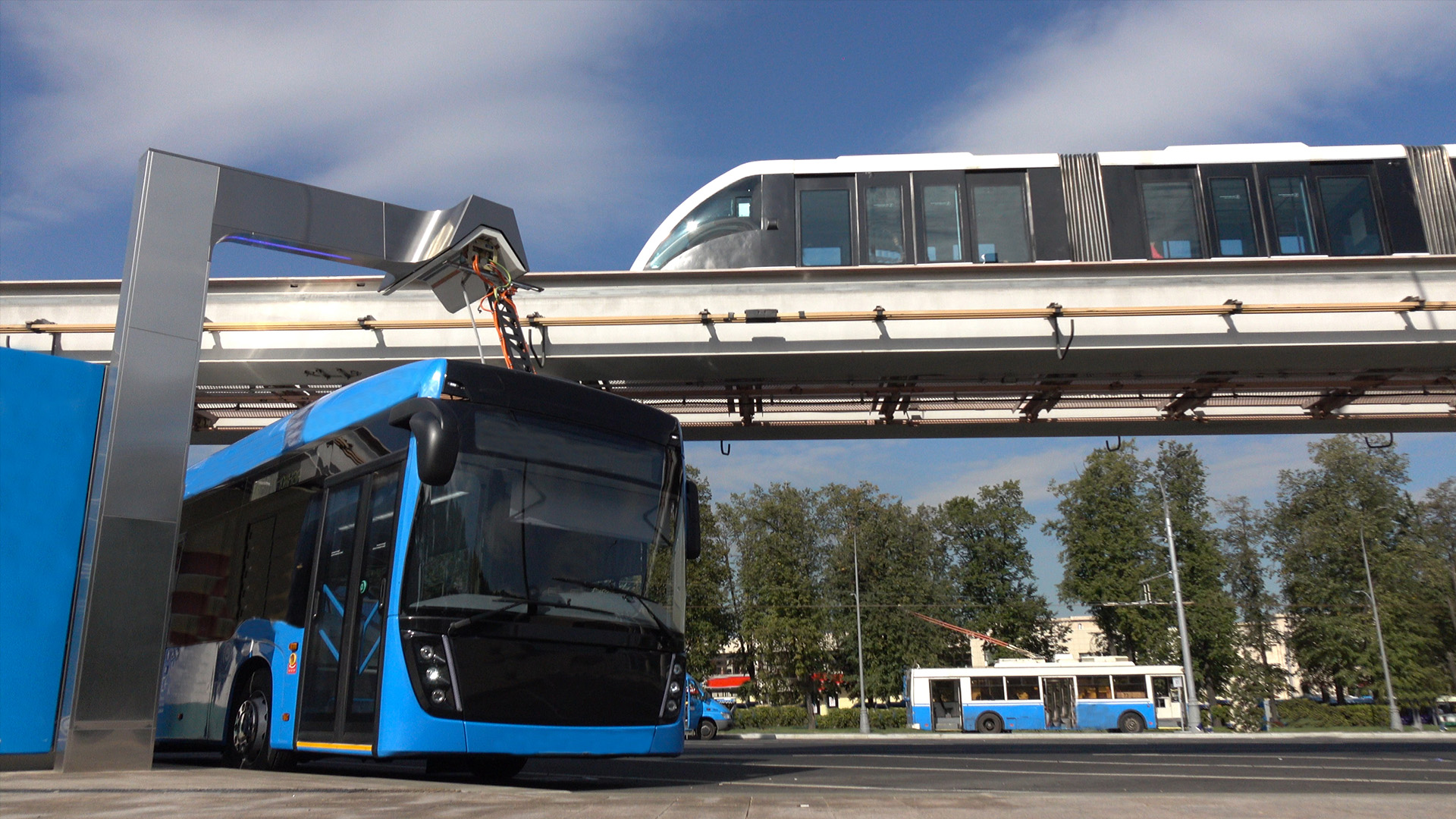Electric bus charges underneath a monorail track
