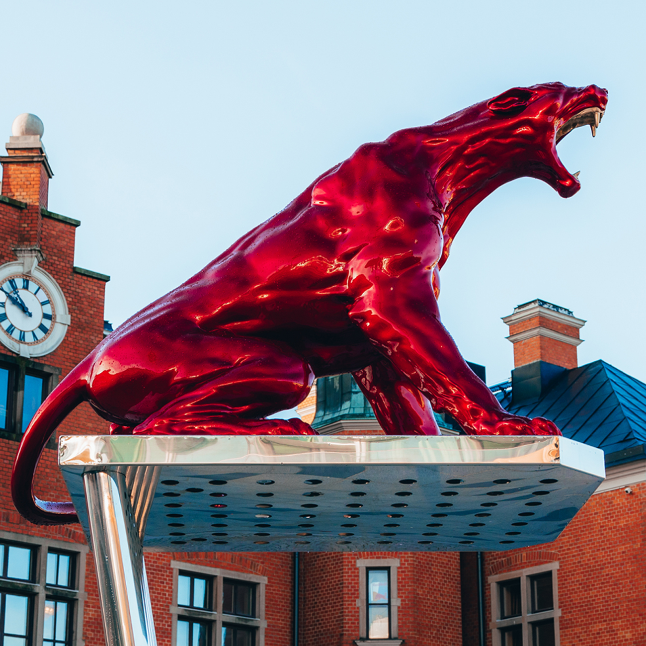 A red shiny sculpture of a roaring puma