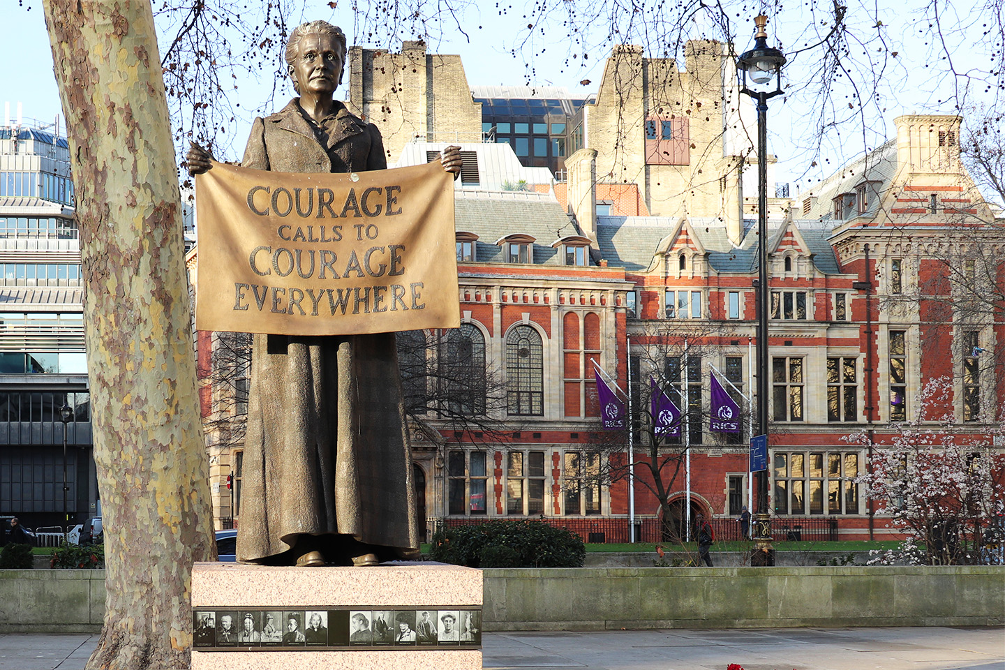 Statue of suffragette holding banner saying courage calls to courage everywhere