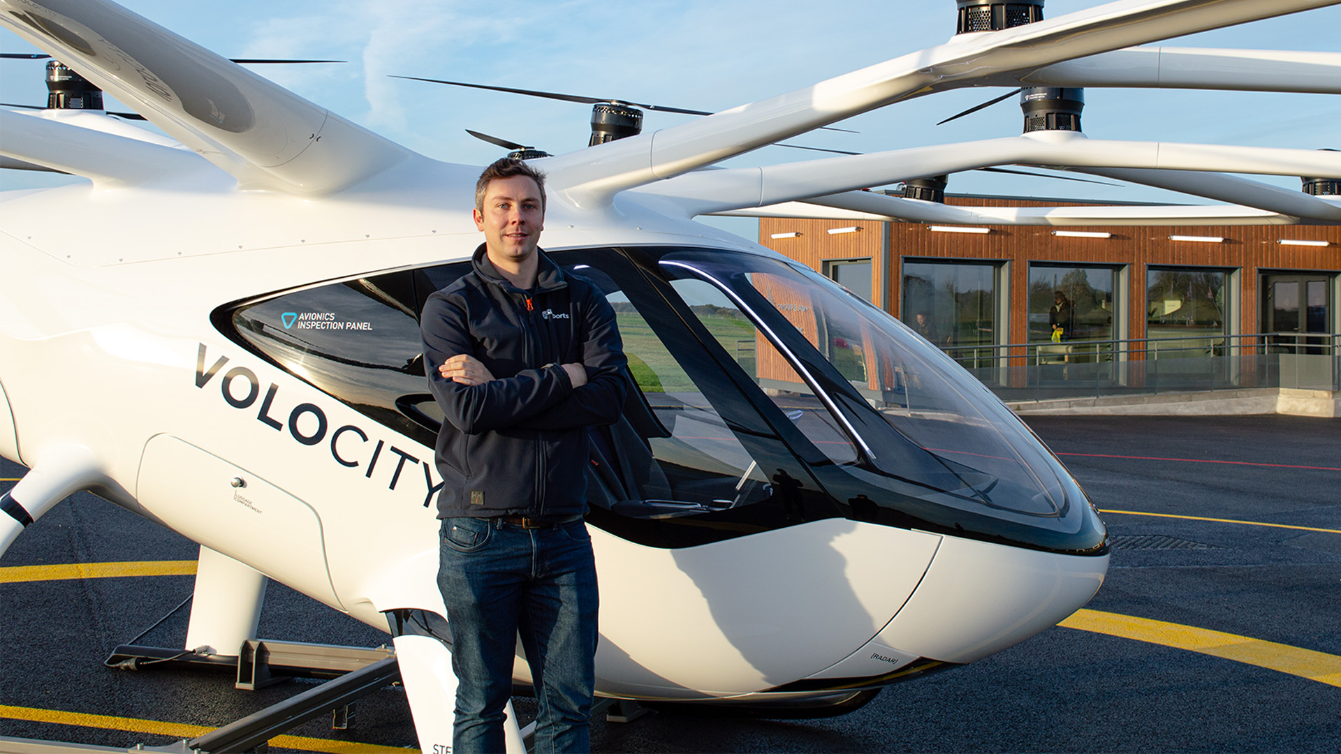 Man stood in front of an electric helicopter at a landing pad