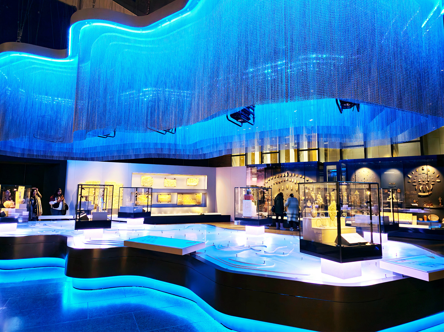 Grand Egyptian Museum exhibit Blue lit up exhibition room filled with Ancient Egyptian artefacts