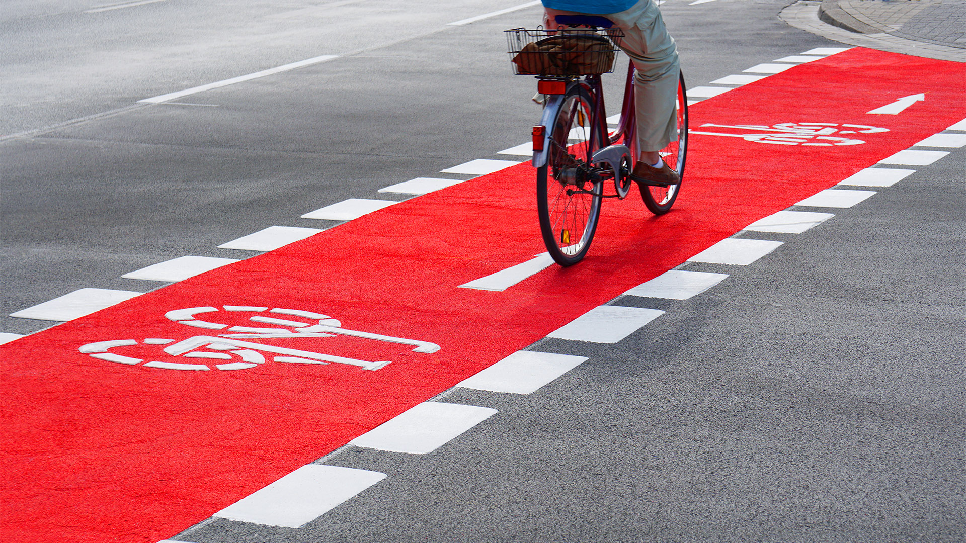 Person cycling down red bike lane