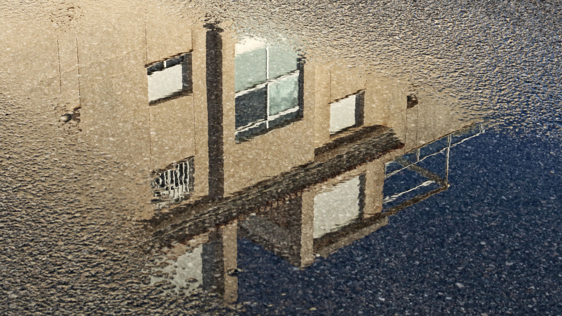 Photo of a reflection of housing in a puddle
