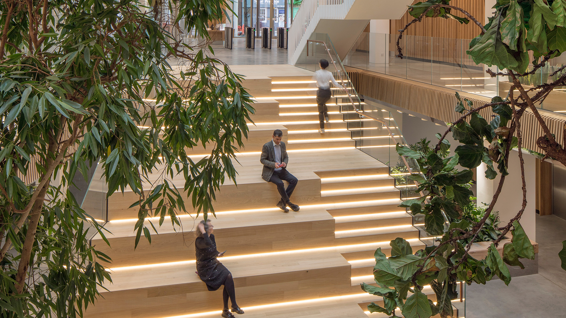 People sitting on wooden hang out stairs in office atrium