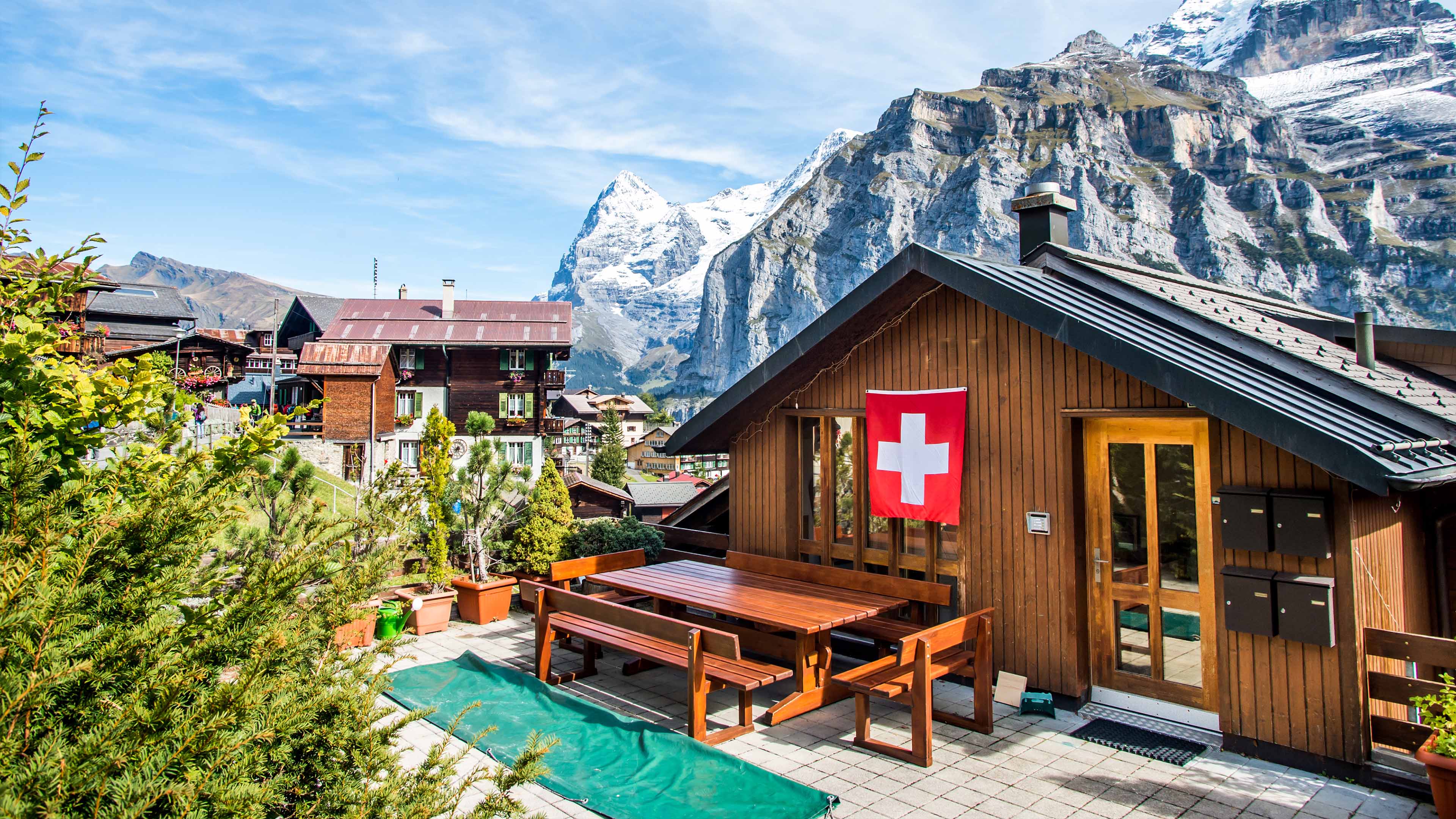 Swiss flag on wooden chalet in Switzerland with snowy mountain backdrop