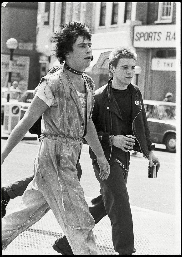 Two men dressed in punk clothes walk down the street in 1977
