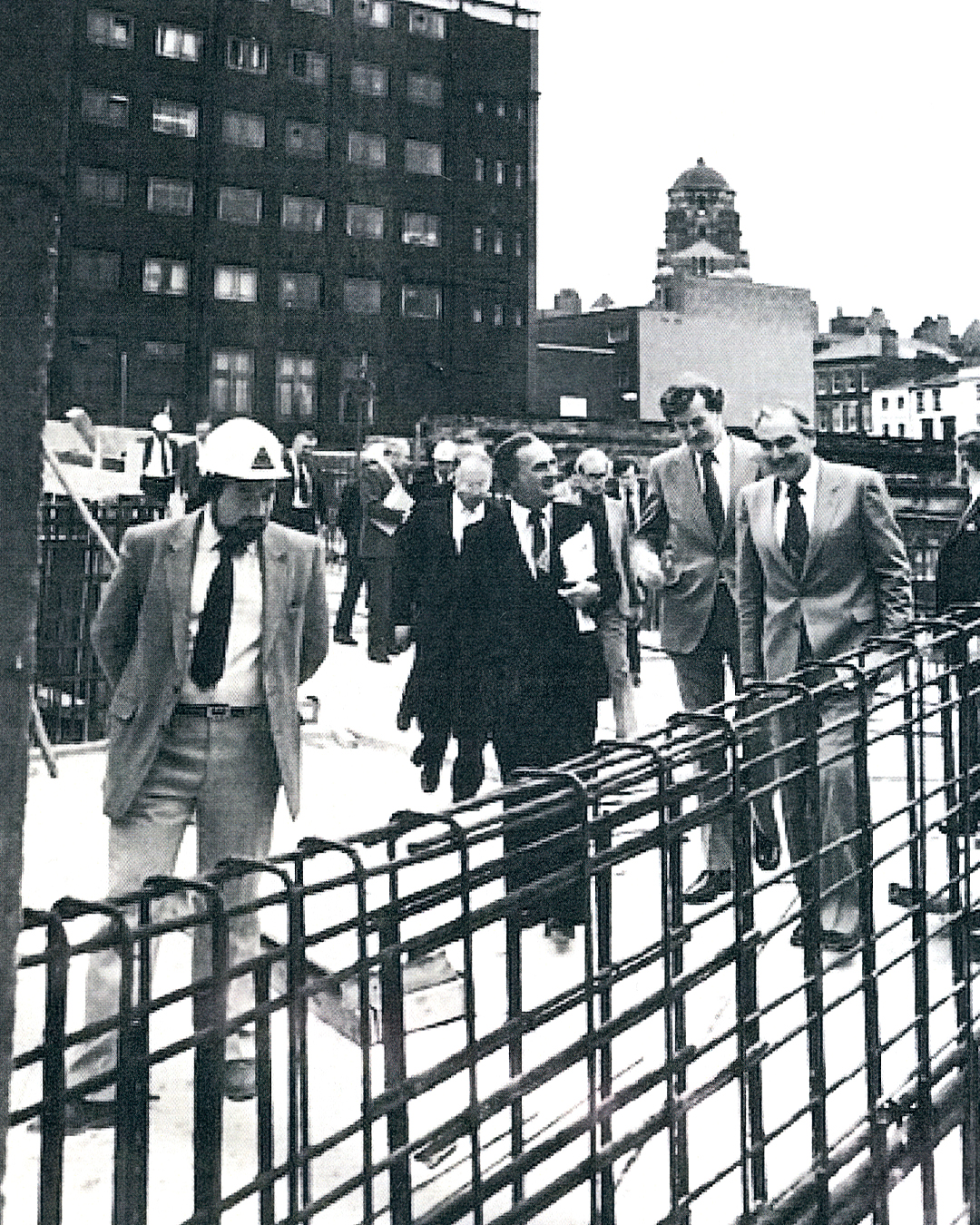 Black and white photo of men in suits on construction site