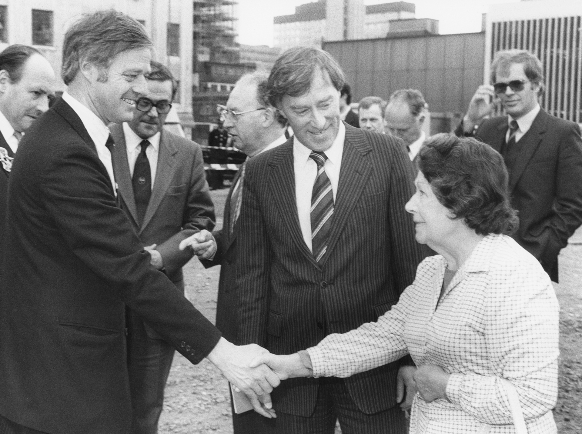 Black and white photo of man in suit shaking hands with a woman