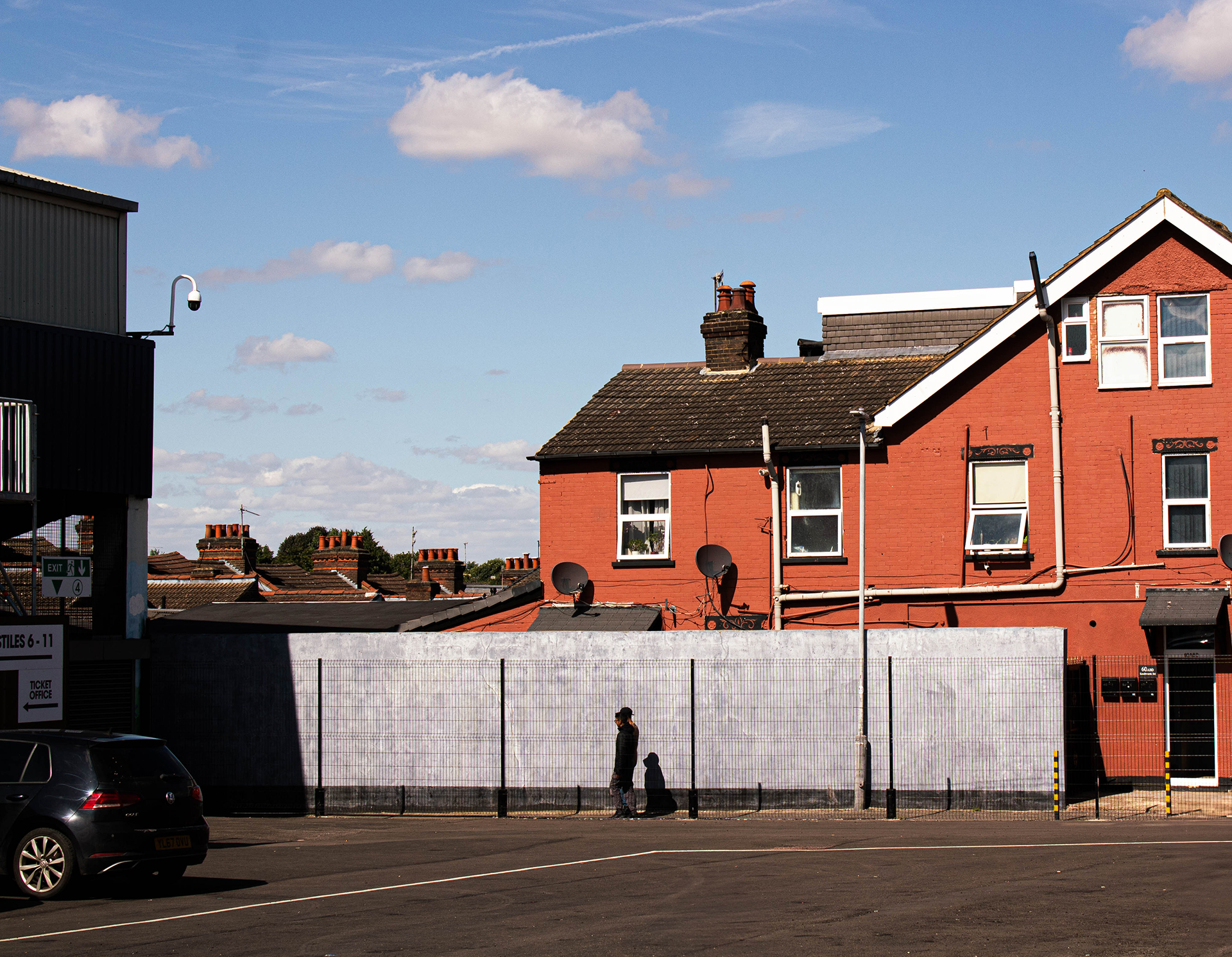 Two people walk down a ginnel alongside a house