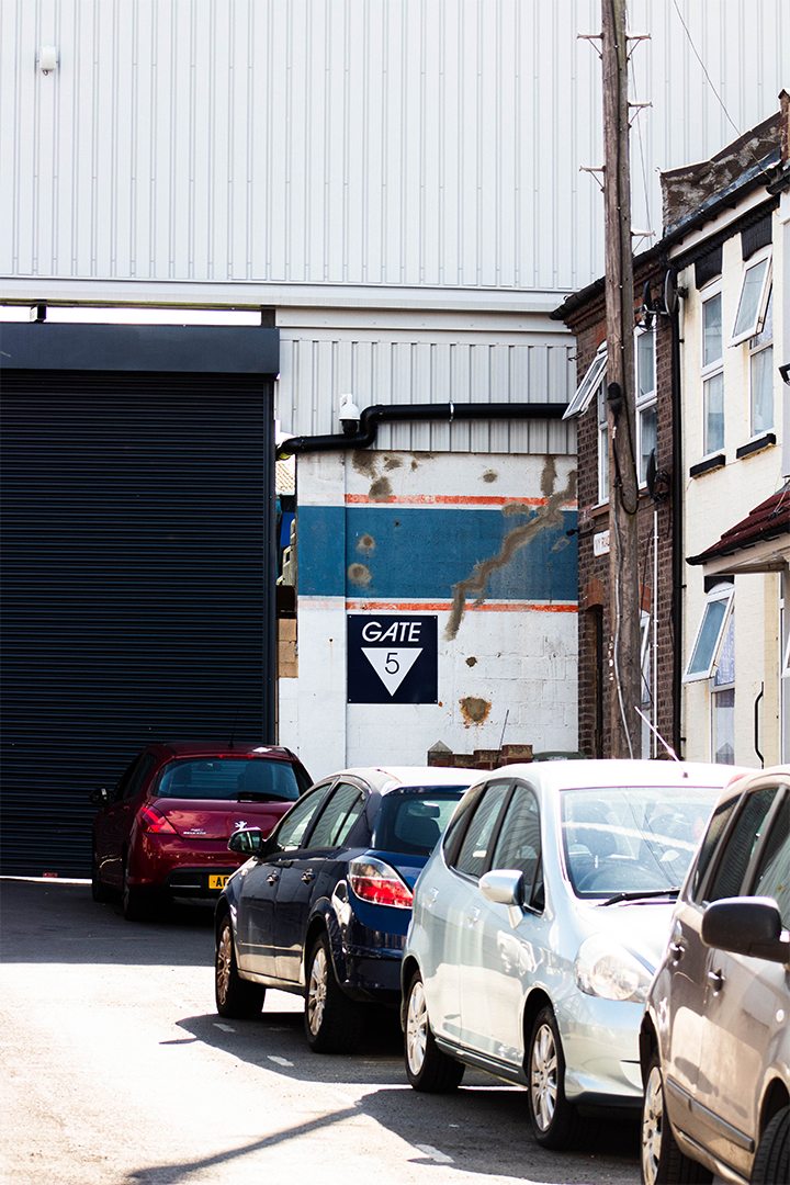 Cars parked along road of terraced houses leading up to Luton Town stadium