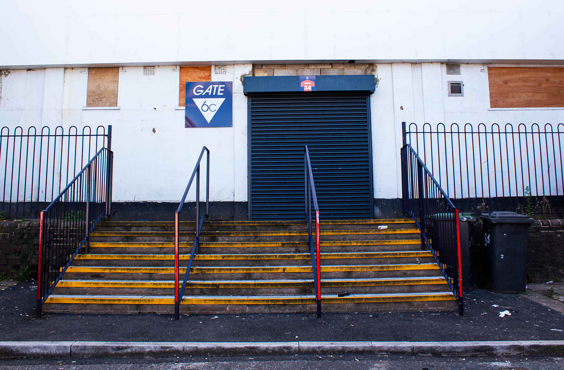 Stairs leading up to blue shuttered entrance to stadium