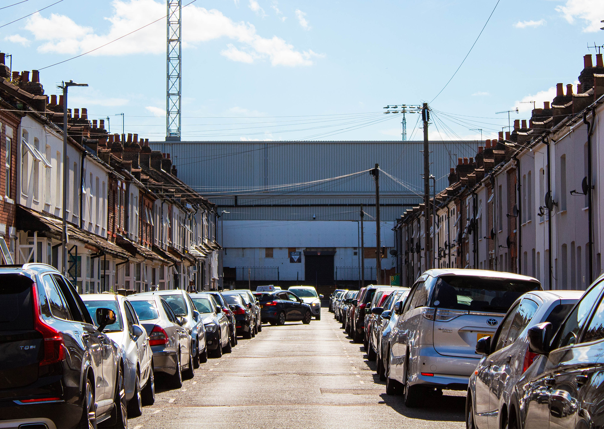 Cars parked along road of terraced houses leading up to Luton Town stadium