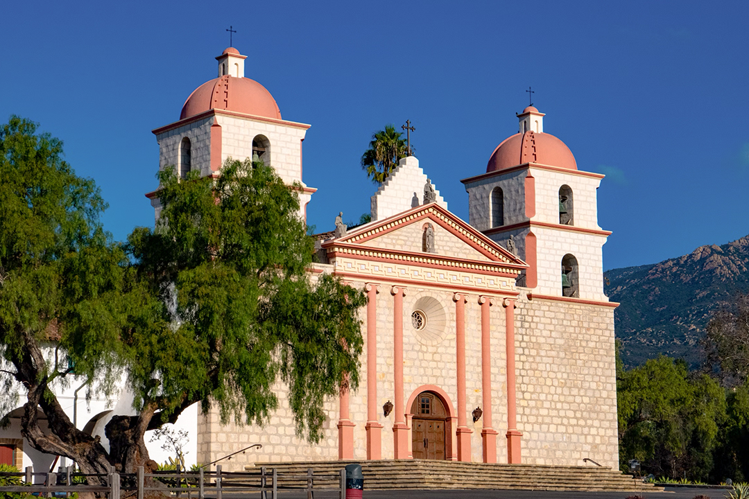 Queen of the Missions A large pink church featuring two prominent towers against a clear sky.
