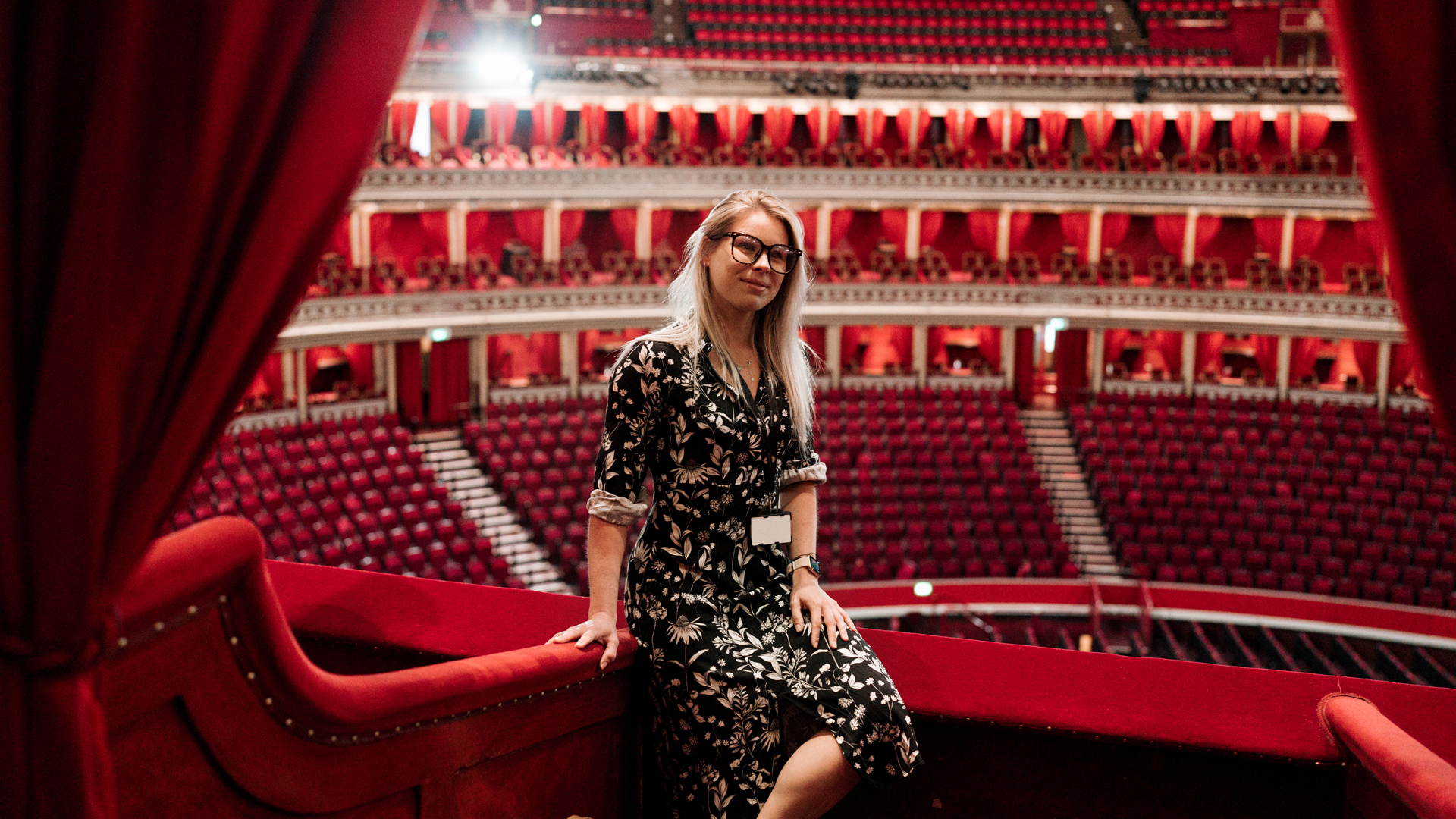 Woman sat on red ledge with backdrop of theatre seats 