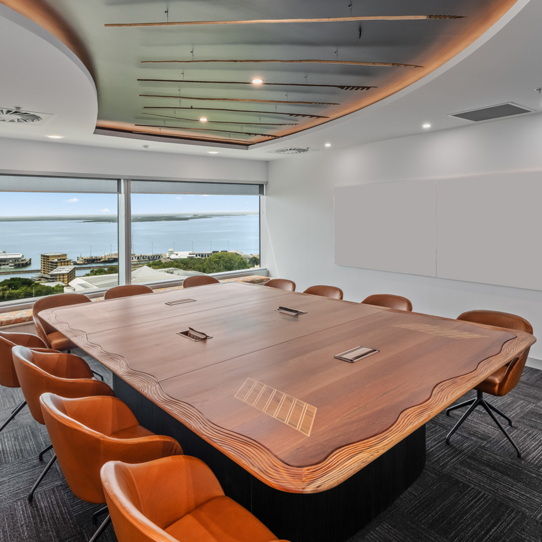 Board room with wooden table, orange leather chairs with windows overlooking water