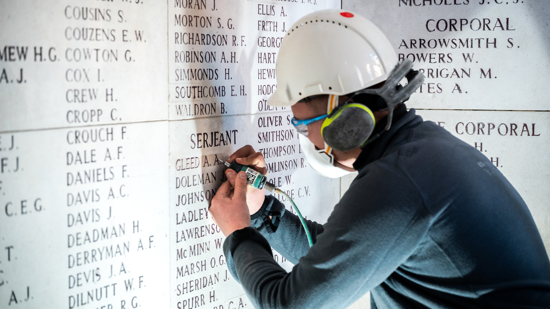 Photo of a person in PPE fixing the engraved names at Menin Gate