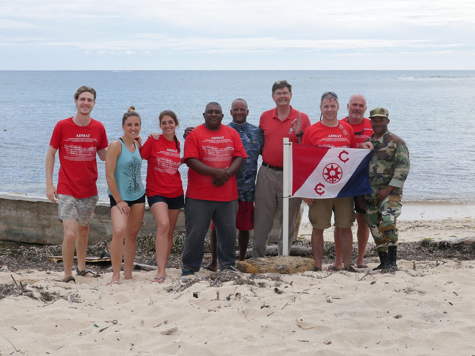 Team of volunteers stood on beach with sea in the background