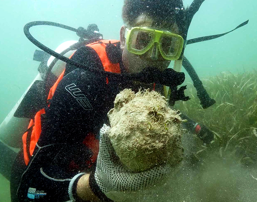 Simon Spooner scuba diving holding an old cannonball