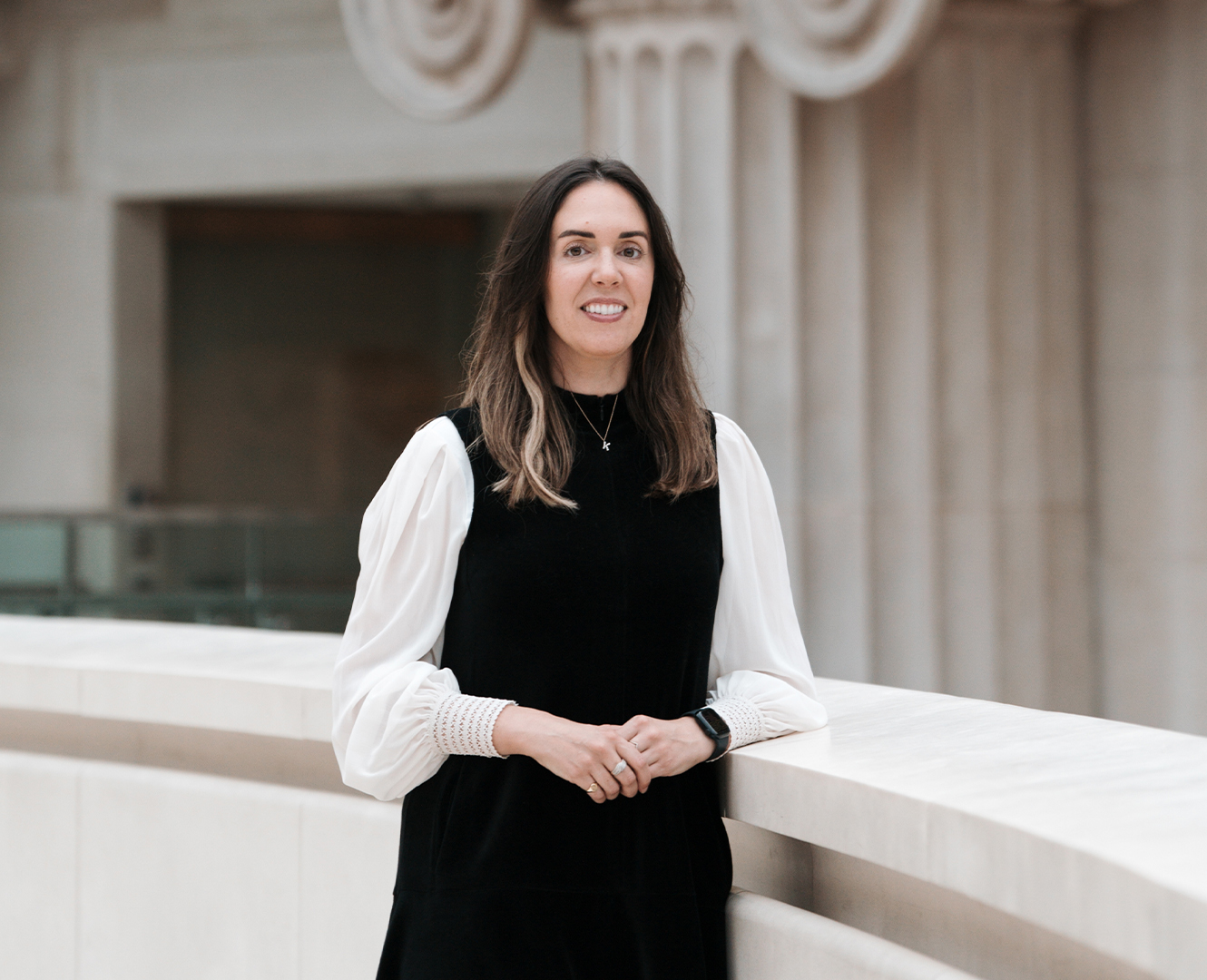 Katharine Cary close up leaning on marble ledge and Greek columns in the background