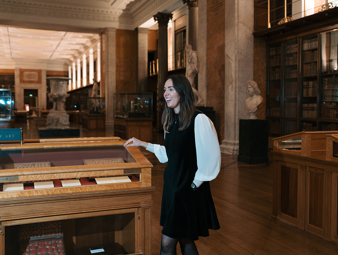 Katharine next to a glass case showcasing artefacts in long corridor room