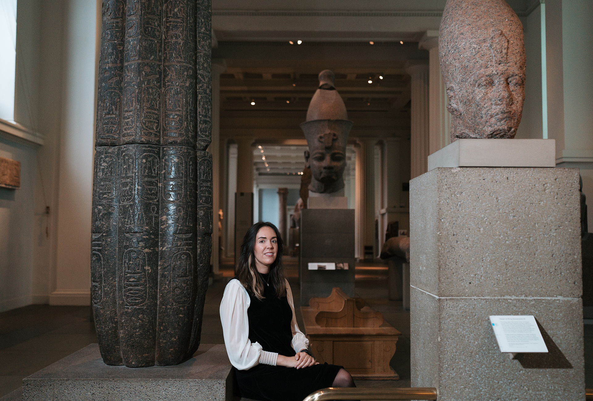 Katharine sits amongst Ancient Egyptian sculptures