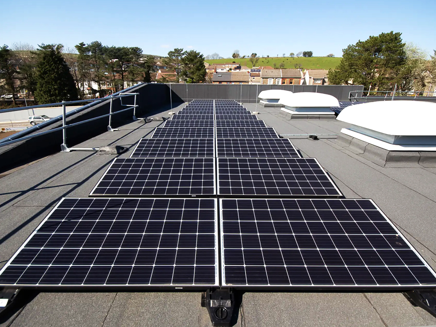 Looking along set of solar panels on top of a flat roof