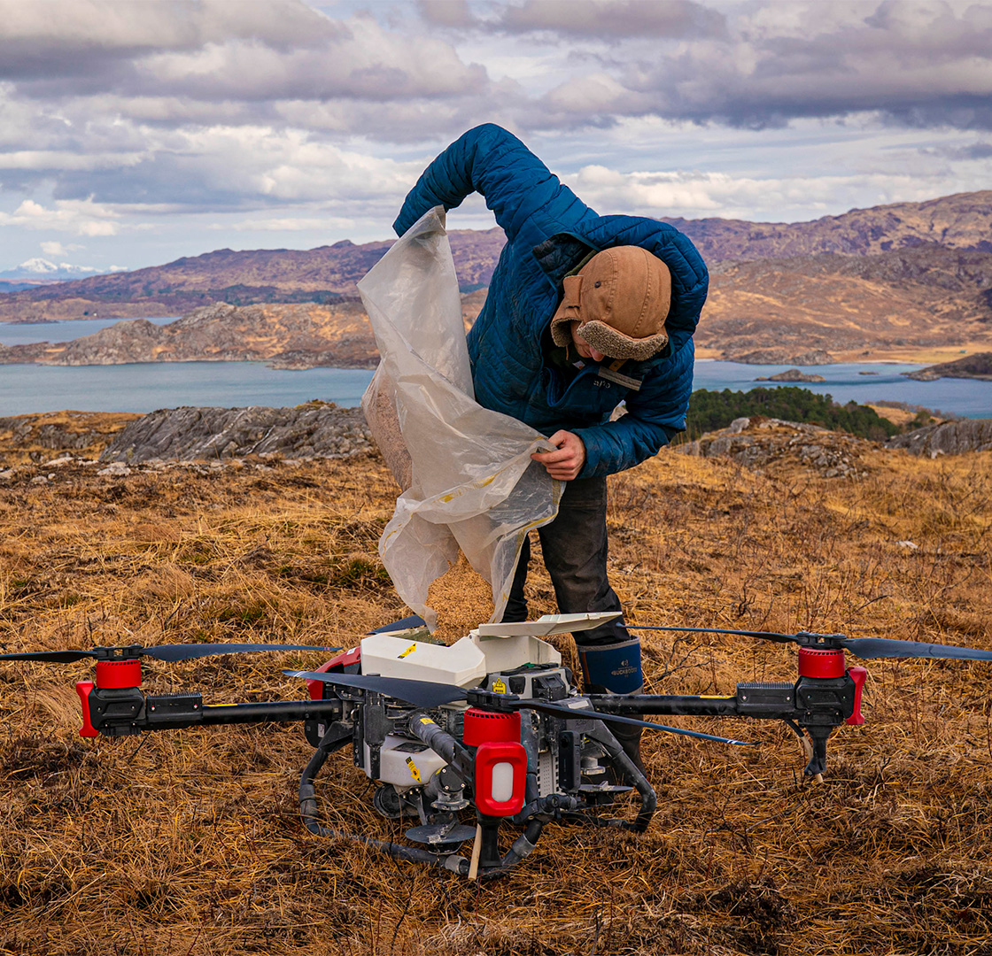 Man filling up a drone with seeds
